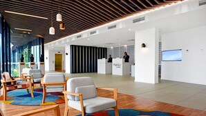 Un moderno vestíbulo de hotel con un mostrador de recepción, zona de estar y un amplio ventanal.