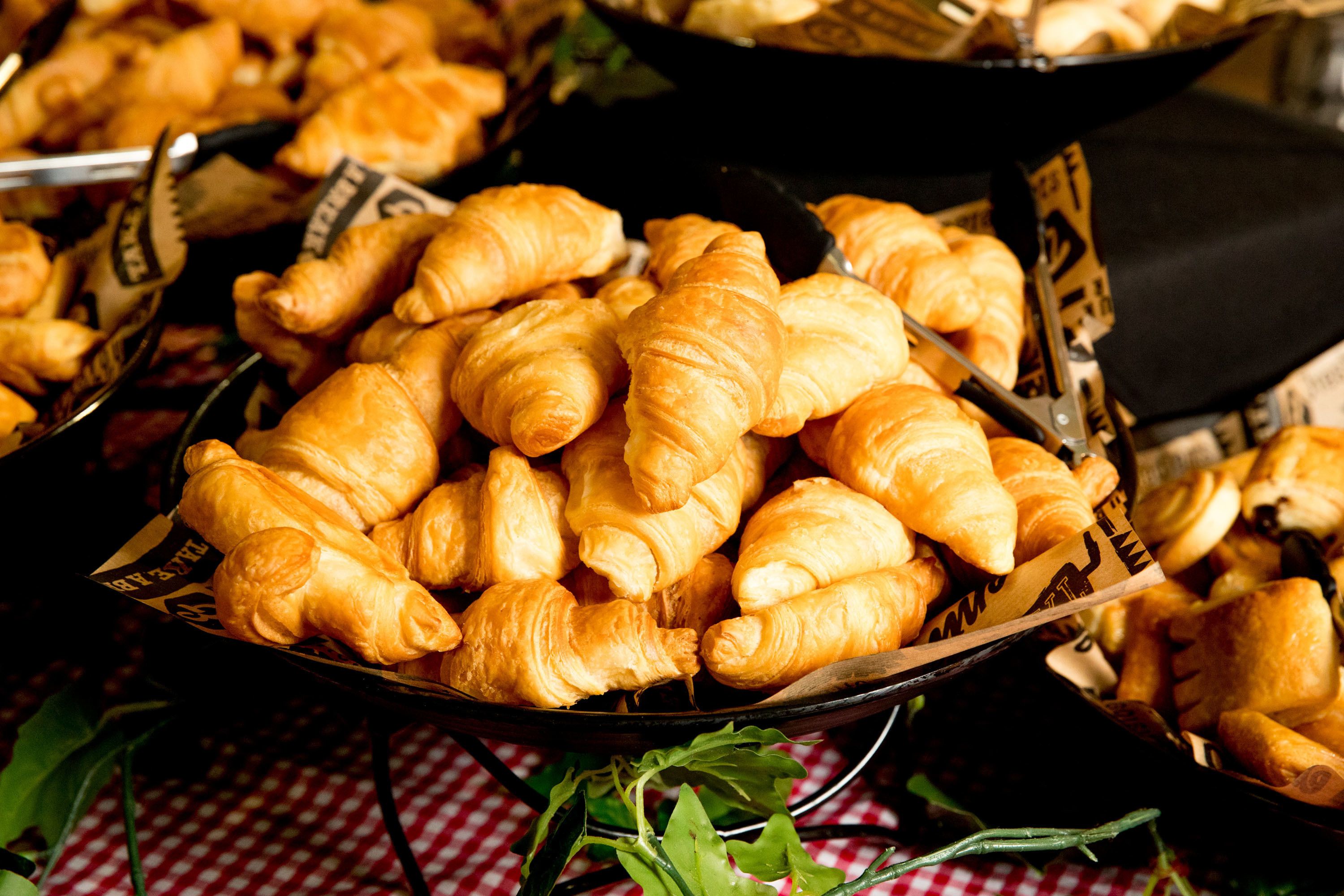 A tray of golden-brown croissants on a checkered tablecloth.