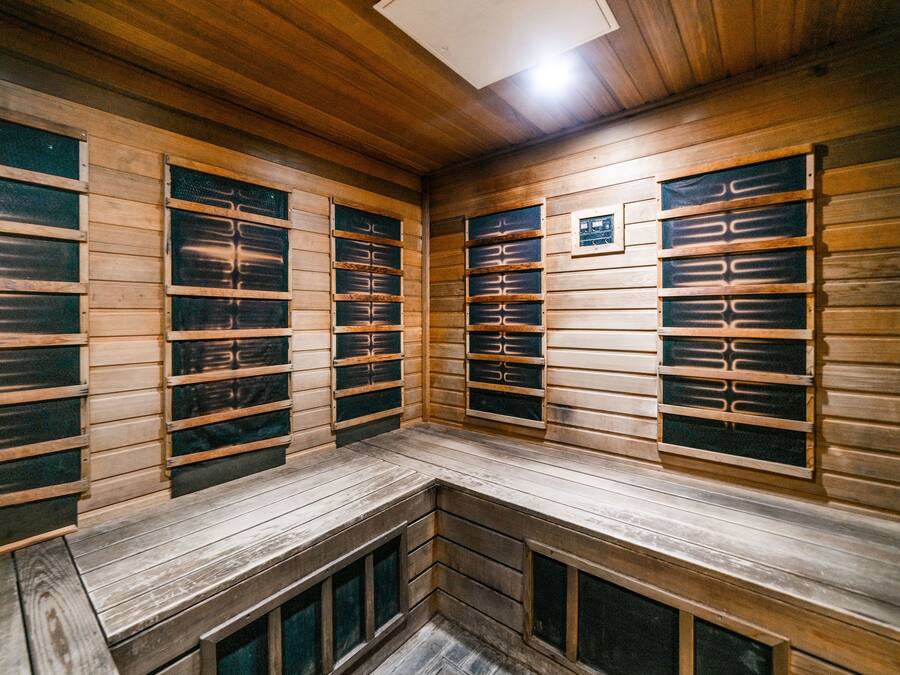 A sauna with wooden benches and multiple benches with glass doors.