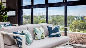 Una sala moderna con un conjunto de sofás y vistas a un paisaje urbano a través de amplios ventanales.
