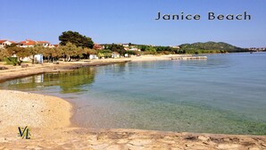 Janice Beach mit klarem Wasser, einem Sandstrand und Häusern im Hintergrund.