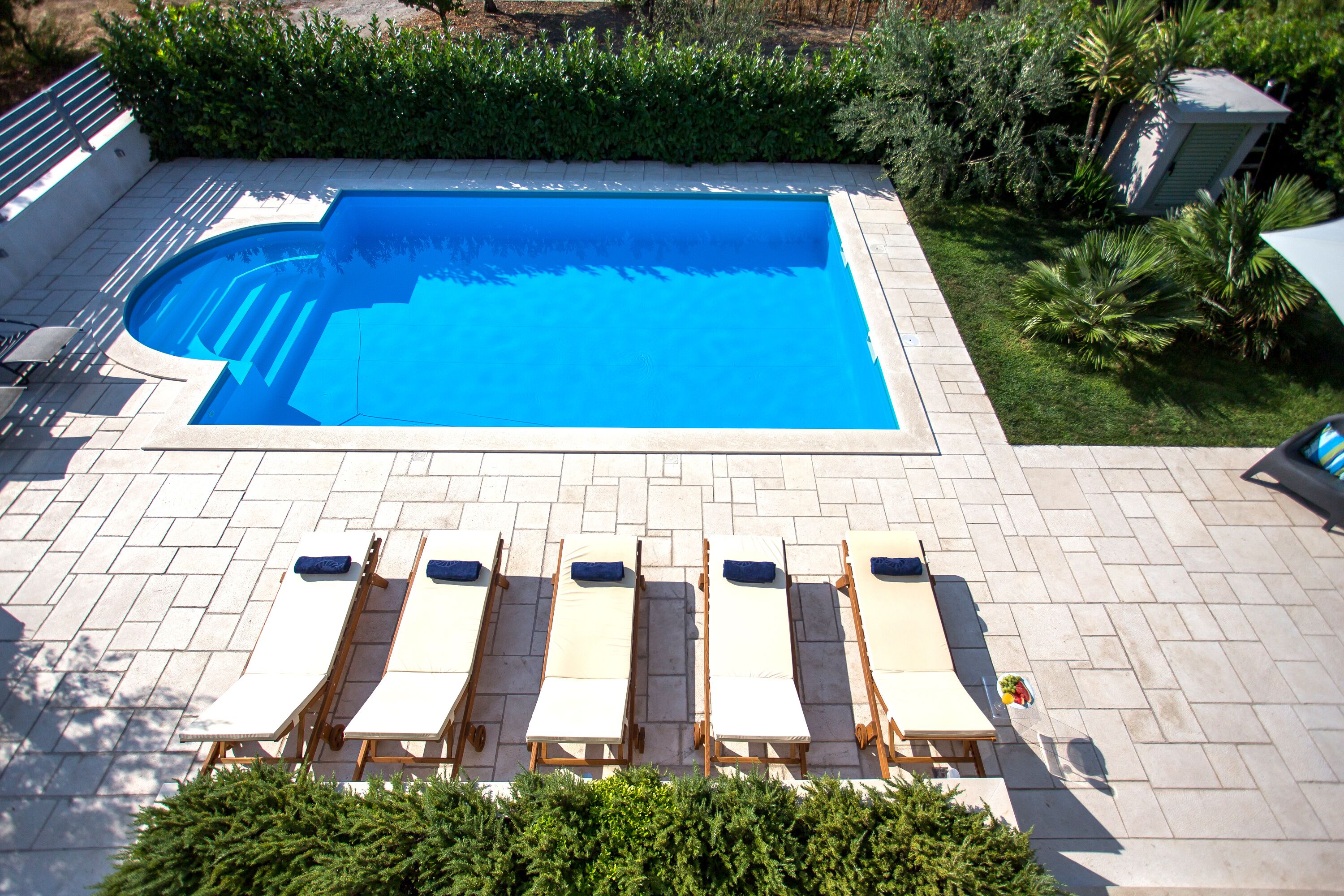 A swimming pool with a tiled deck and lounge chairs.