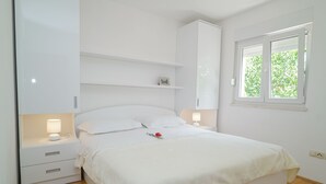 Une chambre à coucher comprenant un lit, des tables de chevet, une commode, une fenêtre et une armoire.