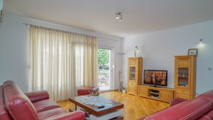 Un salon avec un canapé en cuir rouge, une table basse en bois et un téléviseur posé sur un meuble en bois.