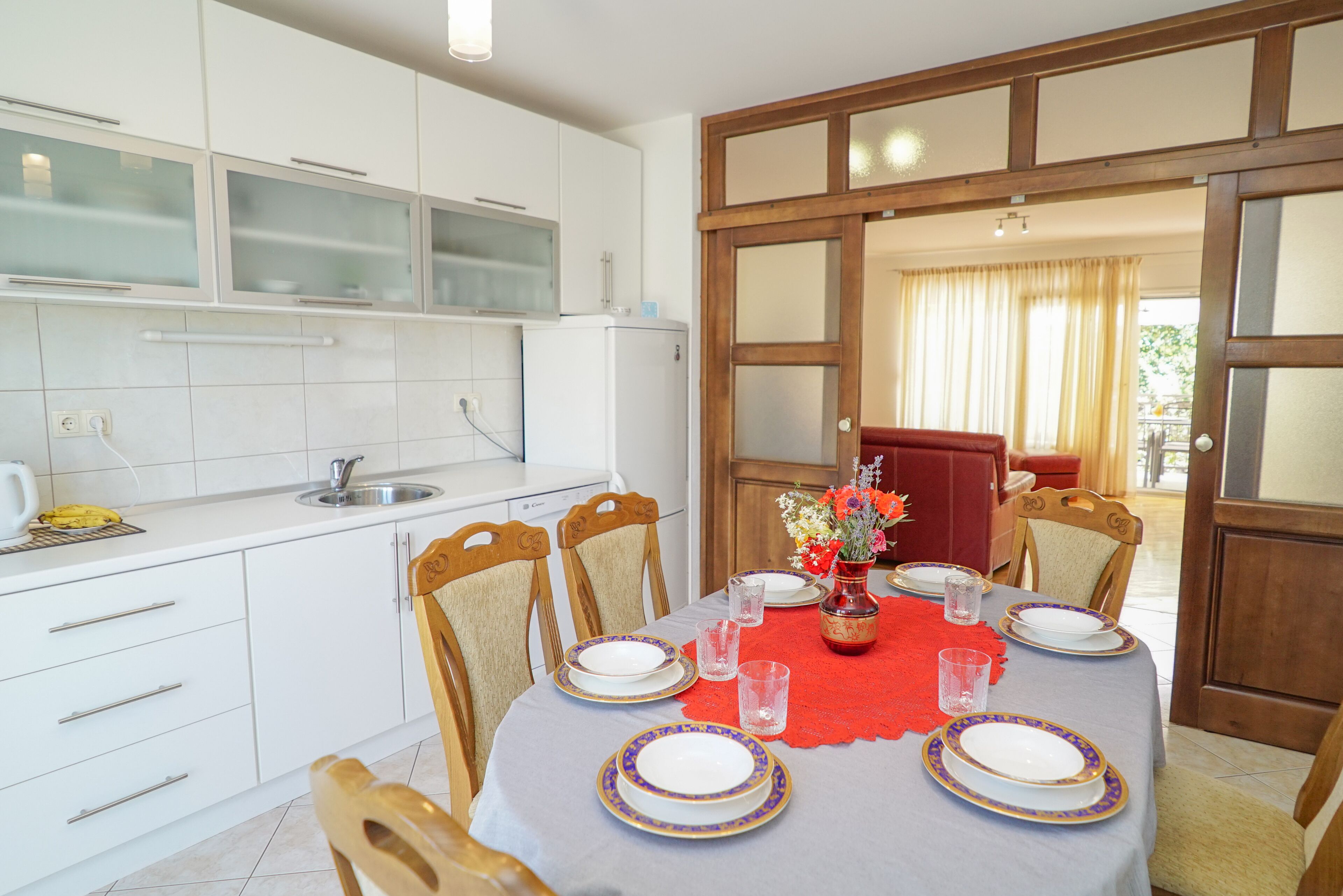 A modern kitchen with white cabinets, a built-in oven, and a dining area with a table set for four.