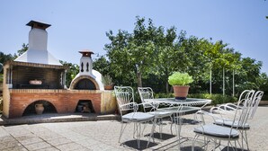 Eine Terrasse im Freien mit einem Backofen aus Ziegeln und Metallstühlen.