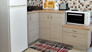 Eine kompakte Küche mit Kühlschrank, Mikrowelle, Toaster und gefliestem Rücksprung.
