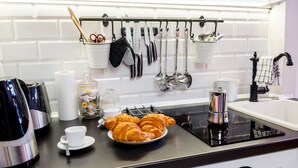 Cozinha moderna com bancada preta, armários brancos e diversos utensílios pendurados em um suporte.