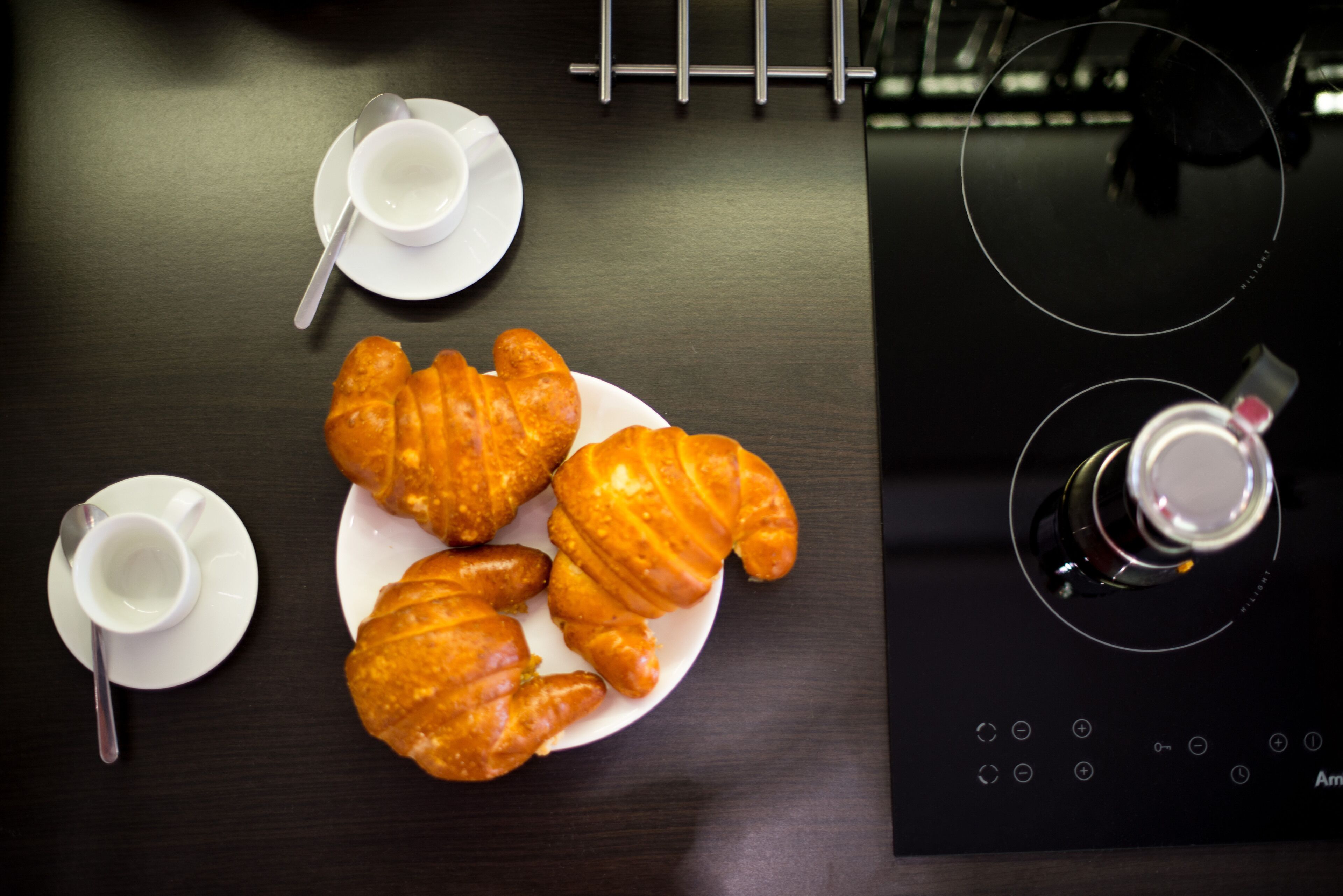 A table with croissants, a cup of coffee, and a bottle of water.