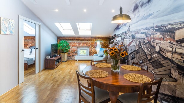 Uma sala de jantar com uma mesa de madeira, jogos americanos trançados e uma luminária pendente.