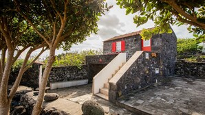 A stone building with a red door and a staircase leading to the entrance. - Adega Velha holiday home, next to the sea and mountains, ideal for couples (Calheta de Nesquim)