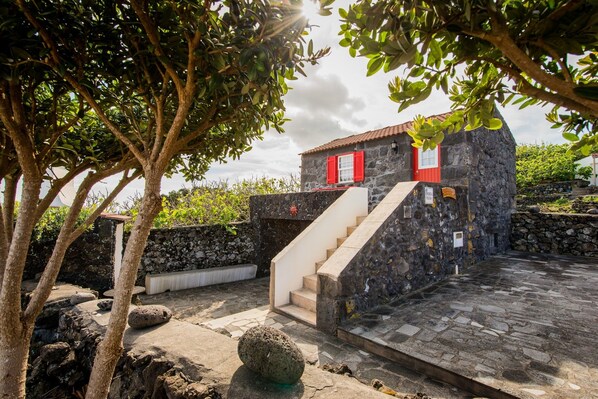 A stone building with a red door and a staircase leading to the entrance.