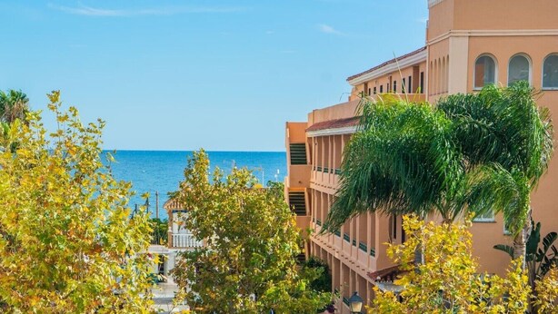 A coastal hotel with a view of the sea, featuring a terracotta roof, balconies, and lush greenery. - Elegant and modern in the center of La Cala, just 100 meters from the beach. (La Cala de Mijas)