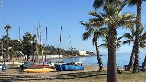 A beach with boats, palm trees, and a clear sky. - Elegant and modern in the center of La Cala, just 100 meters from the beach. (La Cala de Mijas)