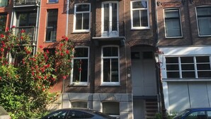 A multi-story residential building with a brick facade, multiple windows, and a visible garage door. - Lovely apartment (2 guests) in city centre Amsterdam -private -quiet -luxurious (Amsterdam)