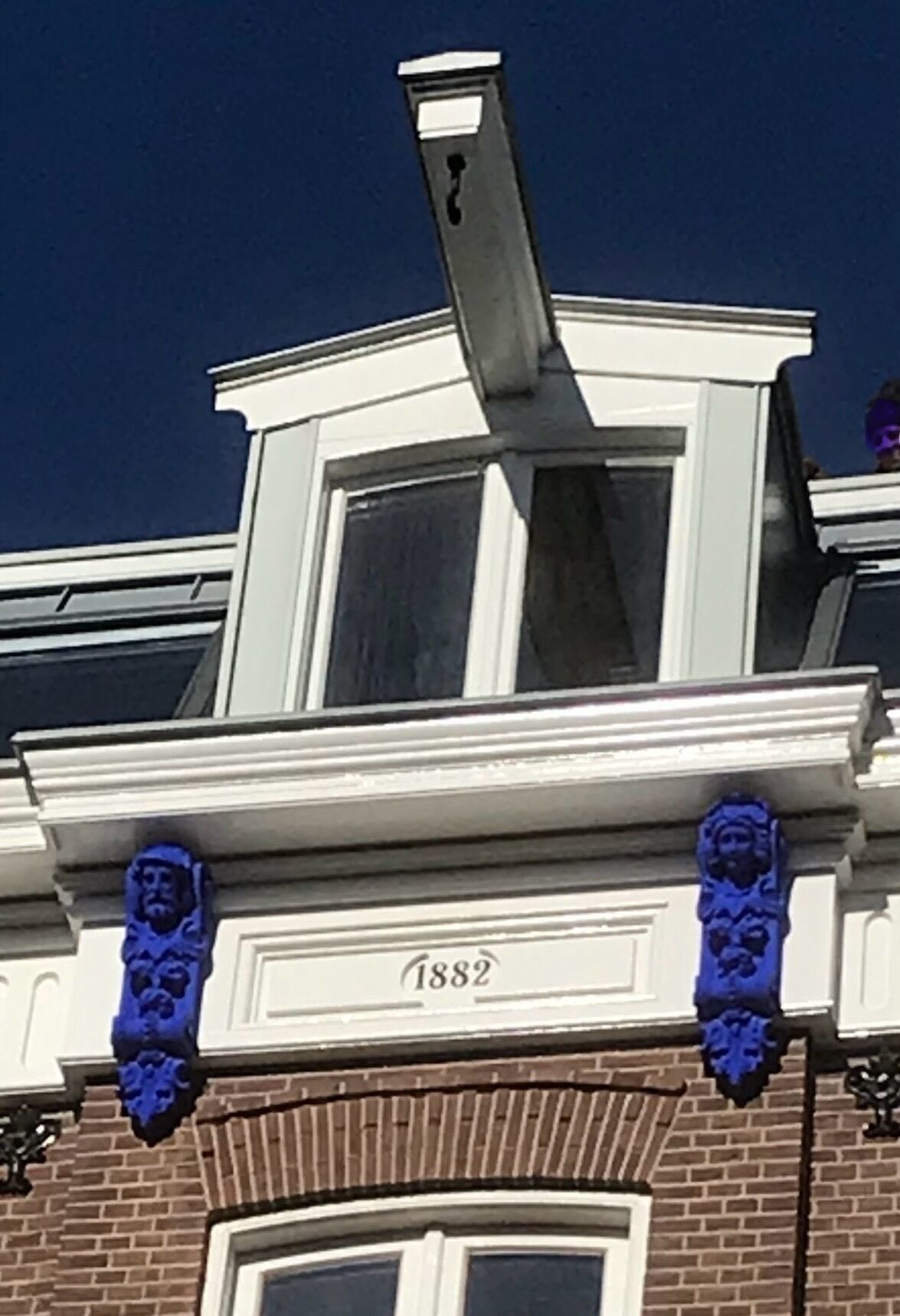 A building with a brick facade, a white window with a black frame, and a number plaque reading '1882'.