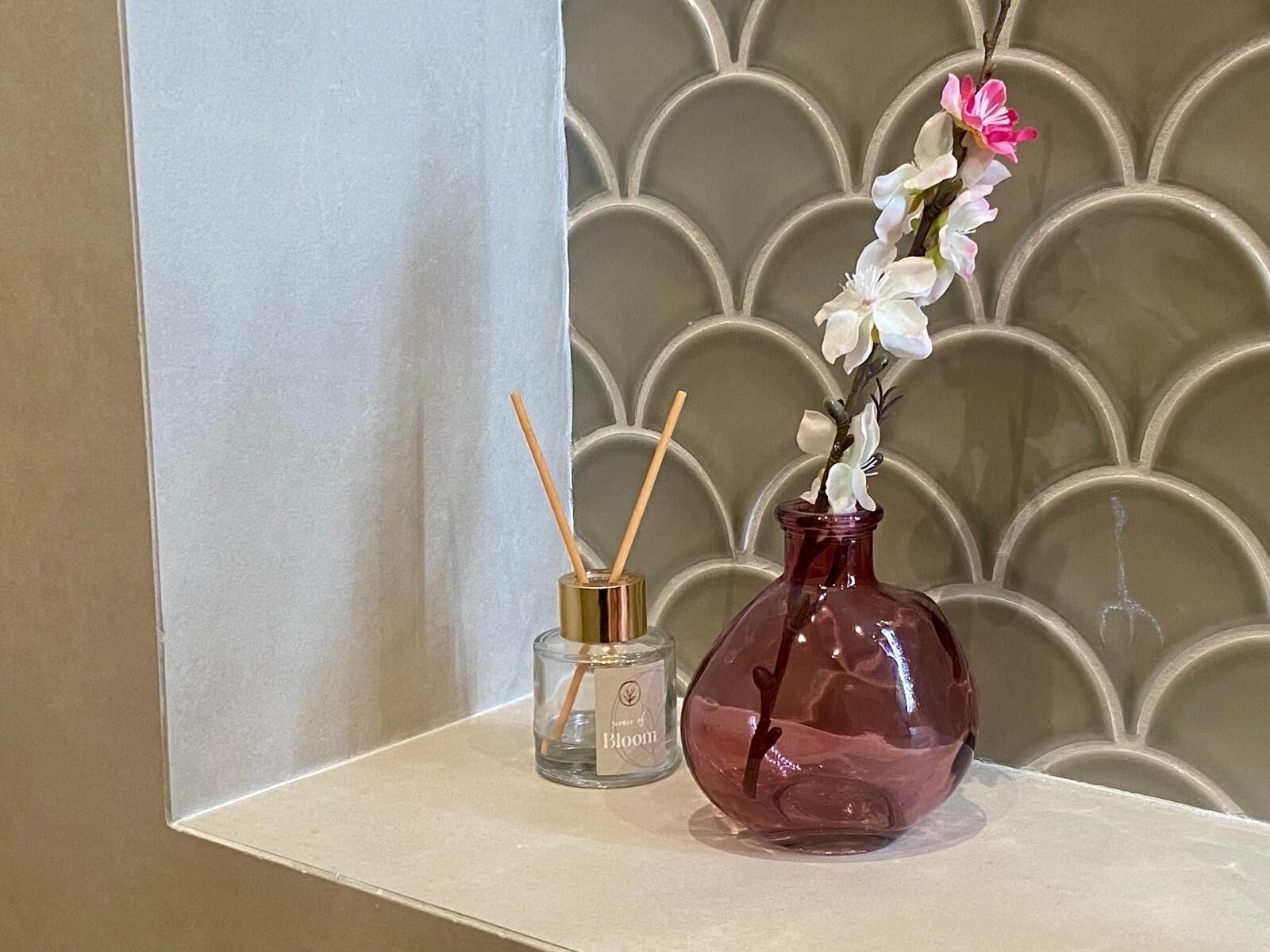 A shelf with a clear glass bottle labeled 'Brom' and a pink glass bottle with a flower.