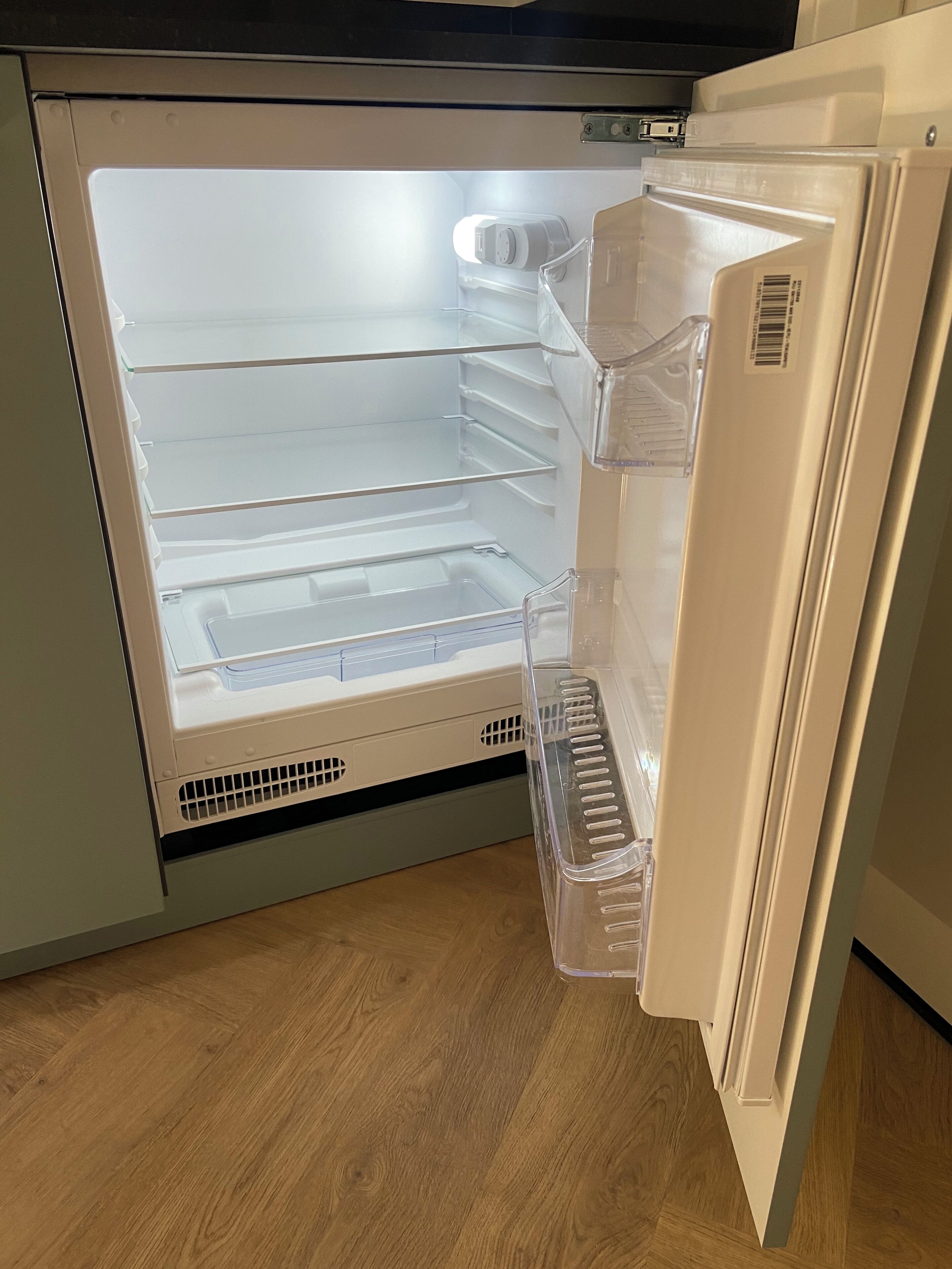 Een open koelkast met heldere planken en een vriesvak.