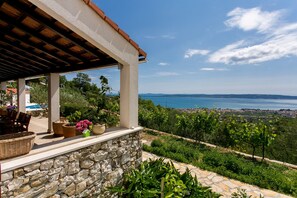 Une terrasse en pierre offrant une vue sur la mer et sur une ville située au loin.