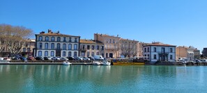 A waterfront with buildings, parked cars, and boats. - Large, spacious ground floor apartment with private terrace and garden area (Agde)