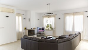 A modern living room with a large sectional sofa, a flat-screen TV, and a fireplace. - Eliofos Luxury Villa - Private Pool, Wifi, BBQ, Smart TV  (Neo Chorio)