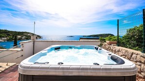 Uma banheira de hidromassagem com vista clara para o mar e um edifício ao fundo.