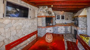 Cozinha rústica com paredes de pedra, teto de madeira e forno embutido.