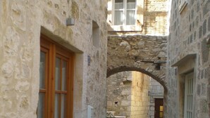 Un estrecho callejón de piedra con una puerta de madera a la izquierda y un arco de piedra en el centro.