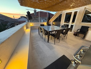 An outdoor patio with a dining table, chairs, and a grill.