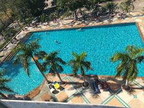 A large rectangular swimming pool with clear blue water, surrounded by palm trees and sun loungers. - View Talay 5D Jomtien Beach Pattaya R192 (Pattaya)