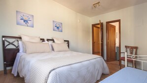 Un dormitorio con una cama grande, dos cuadros de flores en la pared, una puerta de madera y una silla.