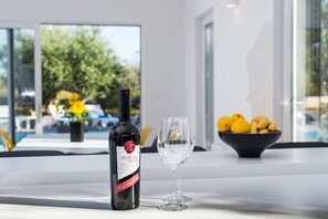 Wine and lemons set on a table amidst a clean, contemporary space with large windows.