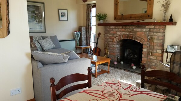 A cozy living room with a fireplace, a sofa, a coffee table, and a dining table.
