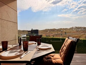 A dining table set with plates, cutlery, and glasses, overlooking a scenic landscape. - T2 Luxury in front of the beach  (Esposende)