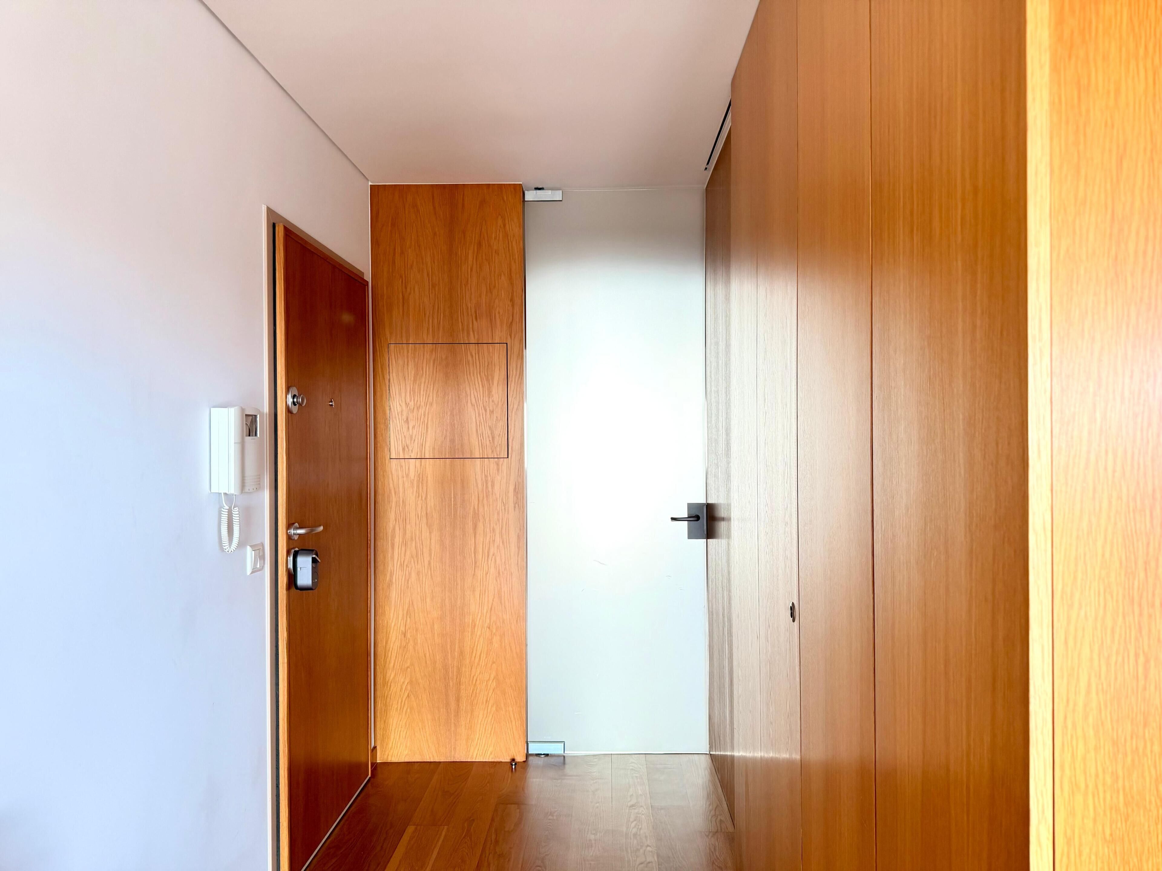 A hallway with wooden doors and a white wall.