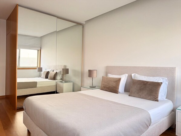 Une chambre d’hôtel moderne avec un grand lit, une table de chevet, une lampe et un miroir.