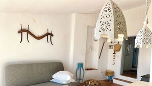 A cozy living room with a sofa, a small table, a hanging light fixture, and a decorative wall piece.