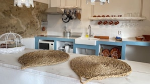 A kitchen with white countertops, hanging pots, a white sink, and decorative lanterns.