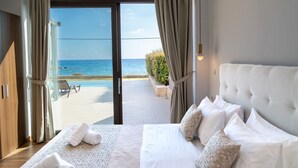 Ett sovrum med en stor säng, utsikt över havet och en uteplats med pool.