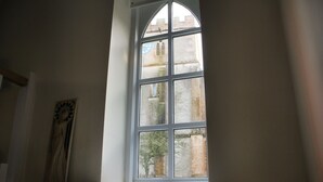 A room with a large arched window overlooking a building. - Romantic & Secluded Cottage. Beautiful Walks & Fantastic Pub (Ashbury)