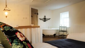 A bedroom with a bed, a nightstand, a dresser, a window, and a bathroom with a sink and mirror. - Romantic & Secluded Cottage. Beautiful Walks & Fantastic Pub (Ashbury)