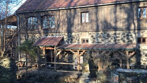 Ein rustikales Steinhaus mit einer Holzveranda und einem Ziegeldach.