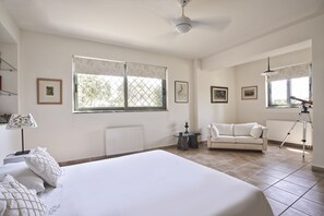 Ein geräumiges Schlafzimmer mit einem großen Bett, einem weißen Sofa und einem Stativ in der Ecke.