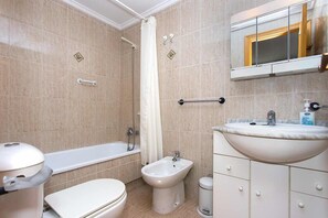 Un baño con bañera, bidé, inodoro, lavabo y espejo.