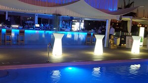 Zona de piscina con bar, asientos, una estatua de Buda y una estructura tipo tienda.