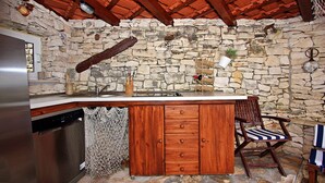 Eine Küche mit Steinwand, Holzschränken, einem eingebauten Geschirrspüler und einer Bar mit einem Stuhl.