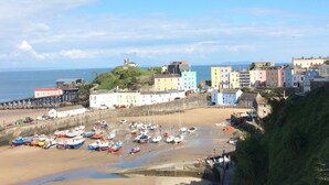Une ville côtière aux bâtiments aux couleurs vives, avec une jetée et des bateaux amarrés sur la plage.