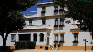 Un bâtiment à deux étages, doté d’une façade blanche et de bordures orange, avec de nombreuses fenêtres et des balcons.