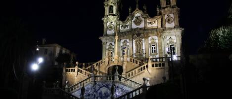 A historic building with a grand staircase and a tiled floor, illuminated at night.