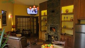 Un salon chaleureux avec une cheminée, des meubles en bois et un téléviseur fixé au mur.